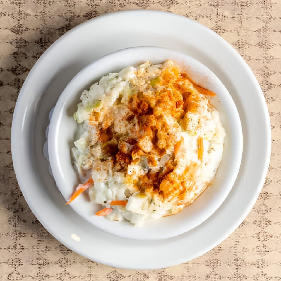 Creamy coleslaw with shredded cabbage, carrots, and a sprinkle of paprika in a white bowl.