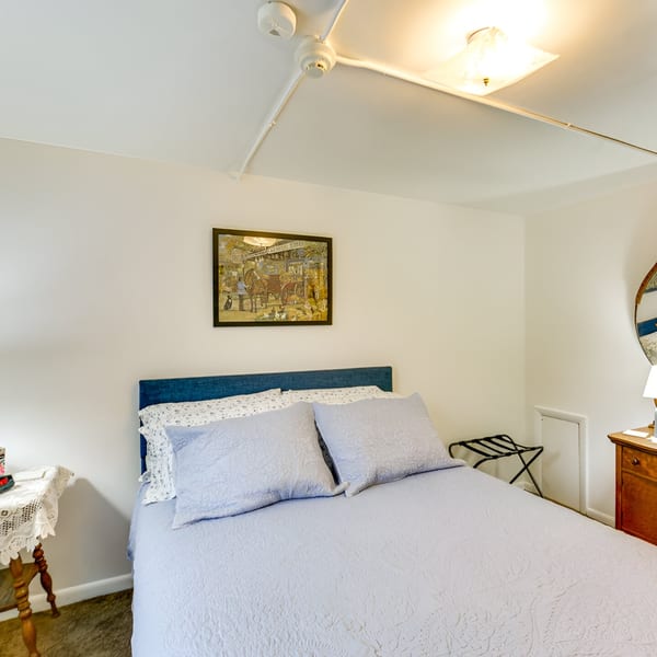 A cozy bedroom at Rockwell’s Red Lion Restaurant with a blue bed, light blue bedding, and a framed picture.